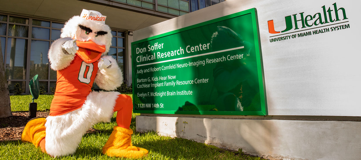 Sebastian the Ibis kneeling by the Don Soffer Clinical Research Center sign