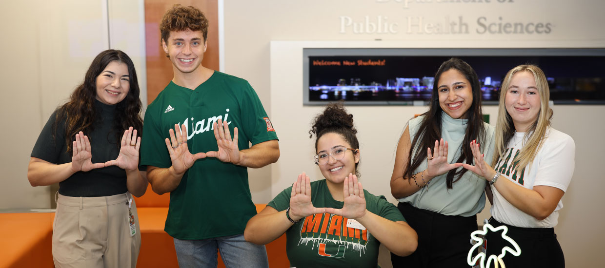 Staff and students doing the U sign at orientation