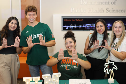 Staff and students doing the U sign at orientation